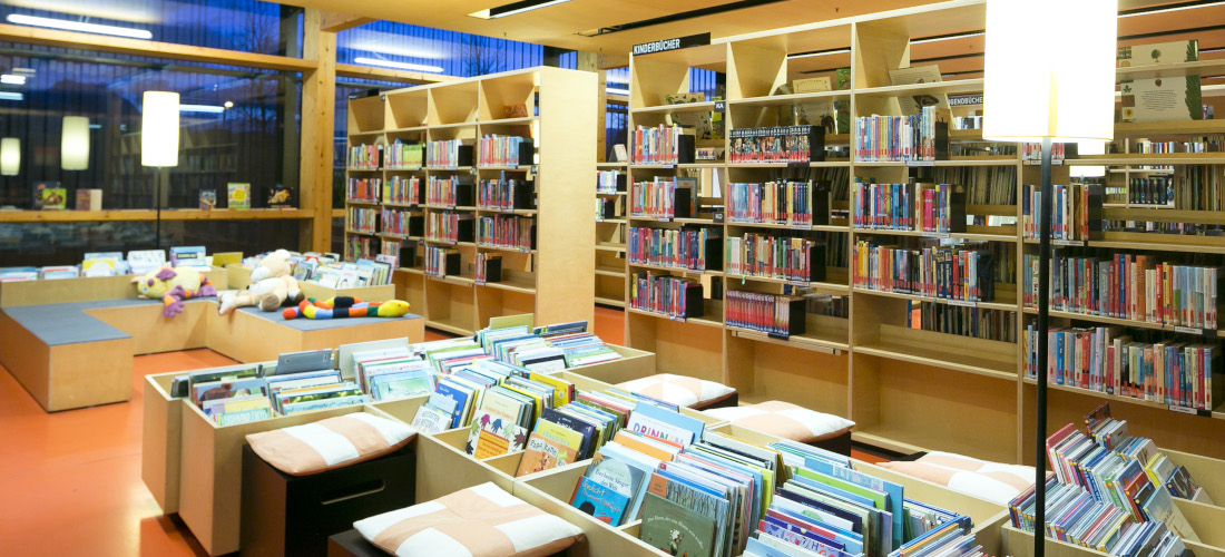 Kinderbereich: Trog mit Bilderbüchern, umgeben von weiteren Bücherregalen